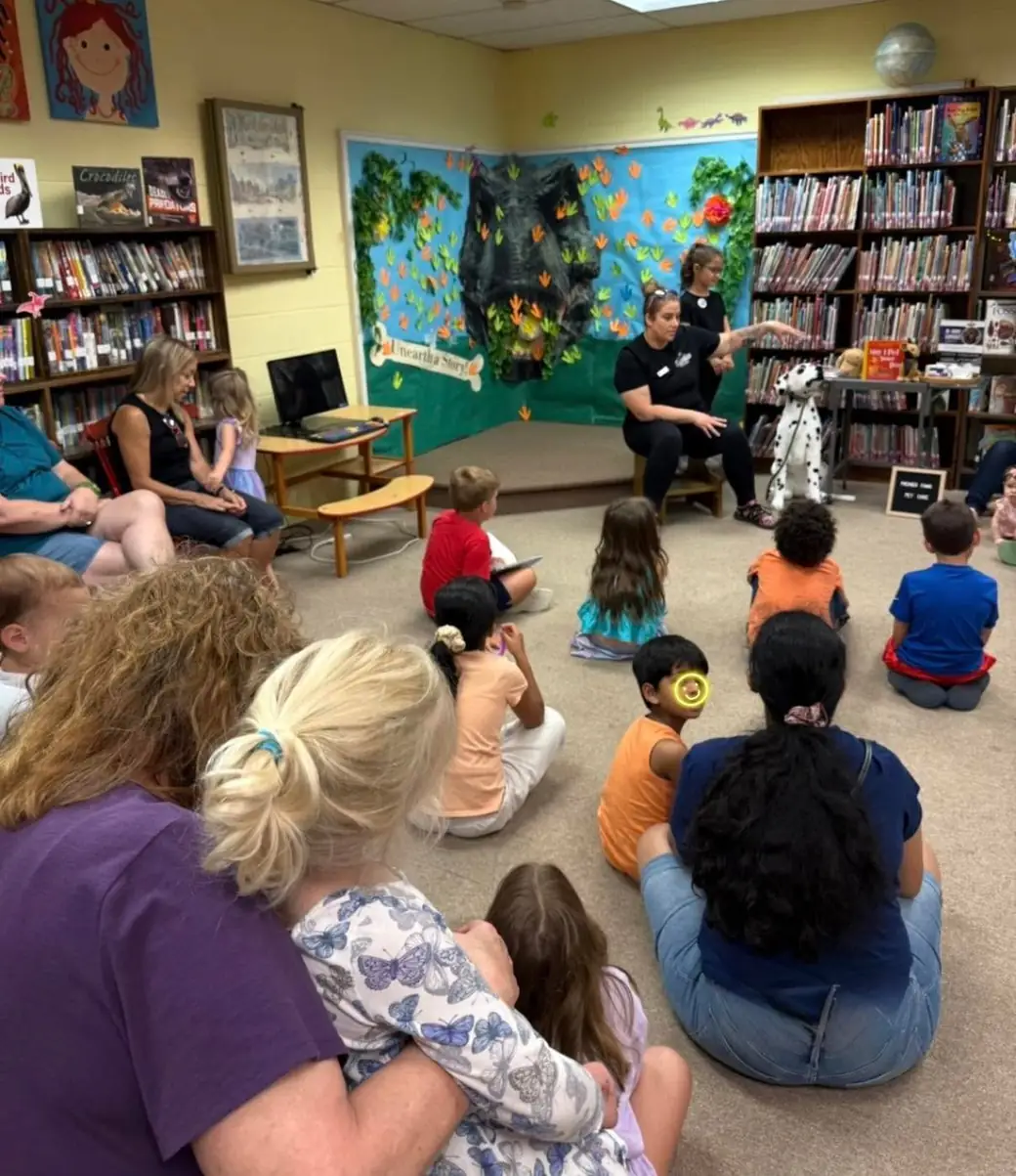 Kids seated on a library floor listening to a Premier Paws presenter during the Safe Dog Skills class